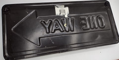 One way metal sign 16 inch long and 1 inch deep with hangers on back.