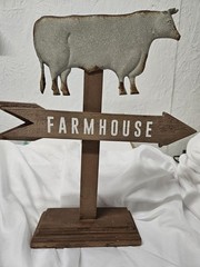 rustic decorative sign featuring a galvanized metal cow silhouette mounted on a